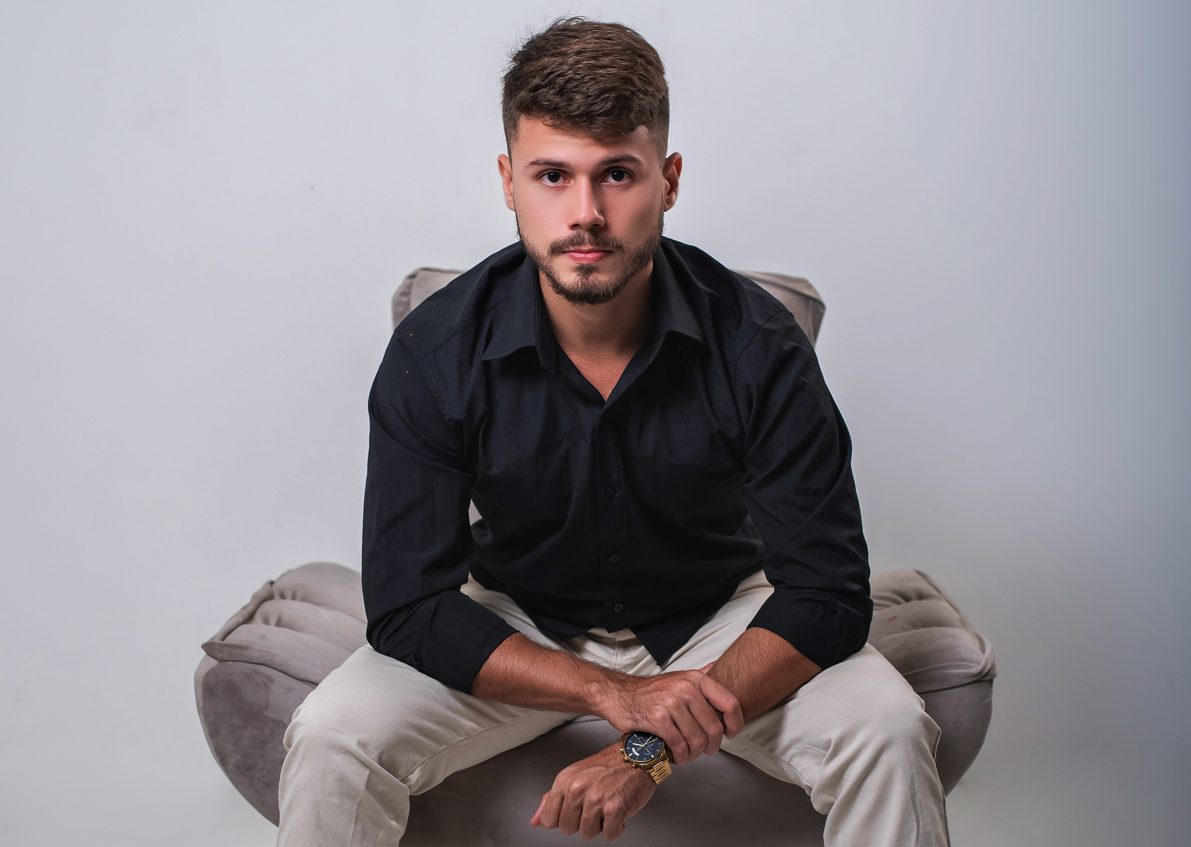 Kevin Paes sitting in a grey armchair, wearing a black shirt, looking at the camera