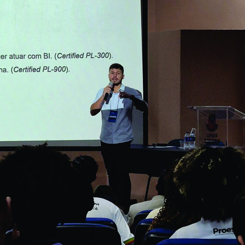Kevin speaking with a microphone in front of a projected slide at a university event